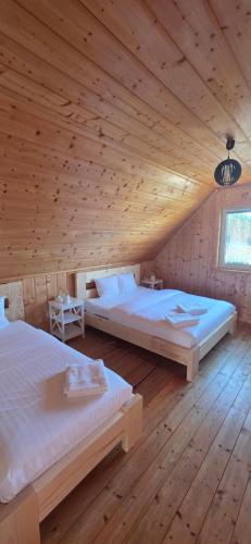 two beds in a room with a wooden ceiling at Ramlejowe Wzgórze - Sauna-Balia in Ostrzyce