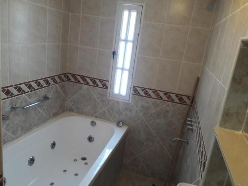 a bathroom with a bath tub and a window at Hotel Teomar in Villa Gesell