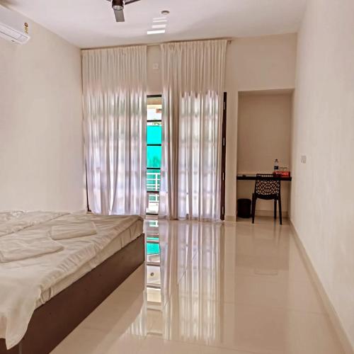 a bedroom with a bed and a table and a desk at Myday Inn by Znormhomes in Varkala