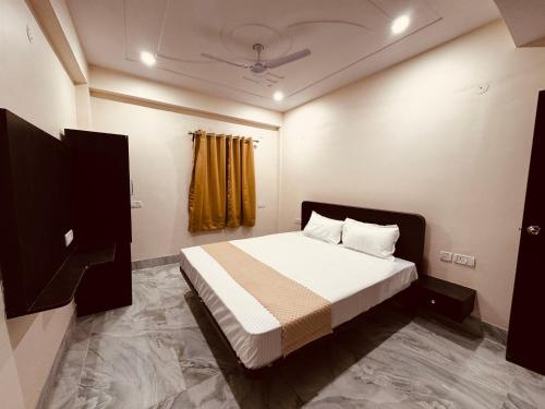 a bedroom with a bed with white sheets and a window at The Aura Grand Hotel and Cafe in Patna
