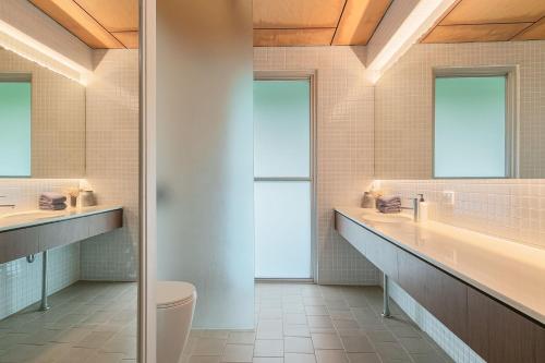 a bathroom with two sinks a toilet and a mirror at Dune Ten in Fingal Head