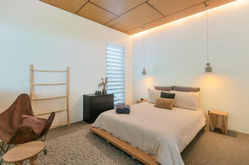 a bedroom with a bed and a chair and a window at Dune Ten in Fingal Head