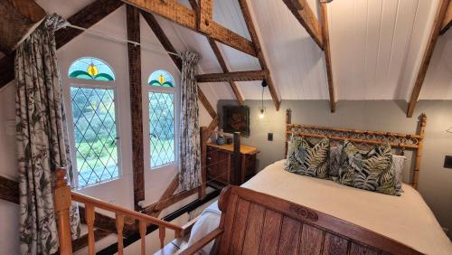 a bedroom with a wooden bed in a room with windows at Lacebark Cottage in Hilton