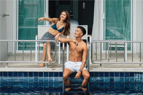 a man and a woman sitting on a fence in the water at Sugar Marina Hotel - NAUTICAL - Kata Beach in Kata Beach