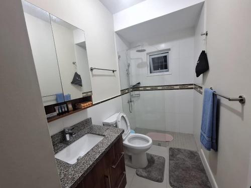 a white bathroom with a sink and a toilet at The Cosy Home in Lucea