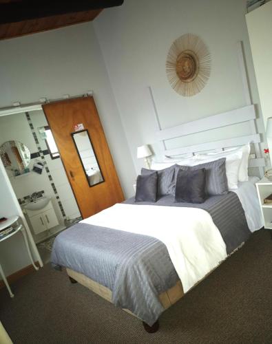 a bedroom with a large bed with blue pillows at At Lilac Cottage, Jeffreys Bay Cozy stay for 2 & Business traveling in Jeffreys Bay
