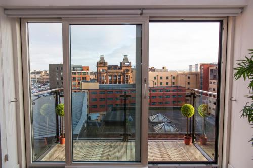 a balcony with sliding glass doors with a view of a city at CITY CENTRE APARTMENT with Free Secure Underground Parking in Glasgow