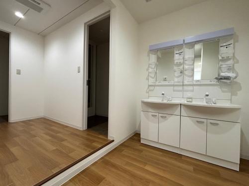ein weißes Badezimmer mit Waschbecken und Spiegel in der Unterkunft TomoHouse in Kutchan