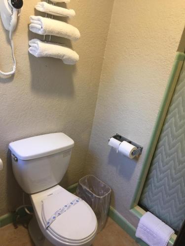 a bathroom with a toilet and a phone and towels at Campbell Motel in Cocoa