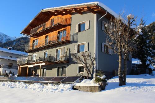 a building in the snow with a tree in front at Gästehaus Kolp in Sankt Anton am Arlberg