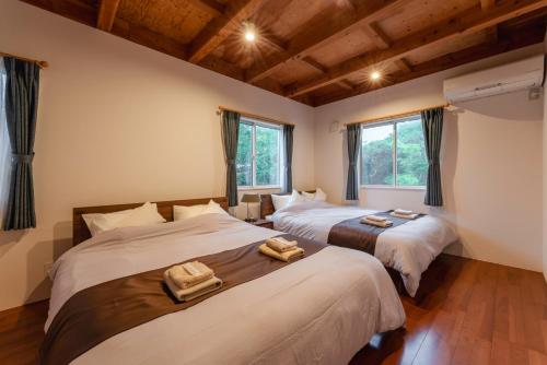two beds in a room with windows at 波の音テラス富津ー海眺望グッドデザイン受賞別荘を最大7名1棟貸切 in Futtsu