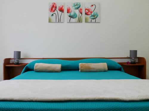 een slaapkamer met een blauw bed met 2 kussens erop bij B&B Le Orchidee in Alghero