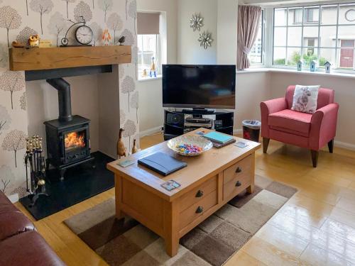 a living room with a fireplace and a table at Cloverfield in Bamburgh
