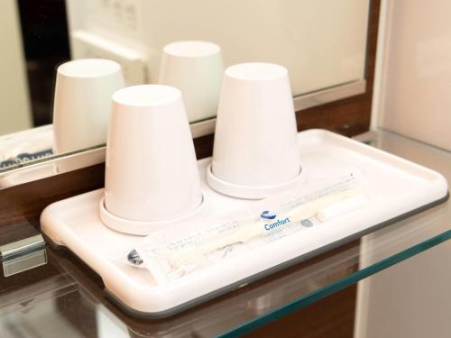 a bathroom counter with two white cups on it at Comfort Hotel Kure in Kure