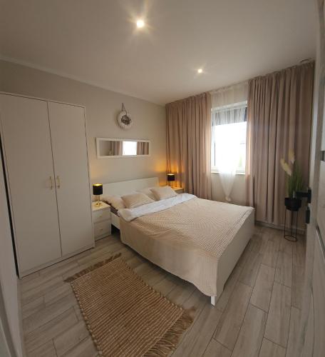 a bedroom with a large white bed and a window at Domki Wenta in Łeba