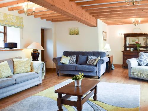 a living room with two couches and a table at Scarr House Farm in Muker
