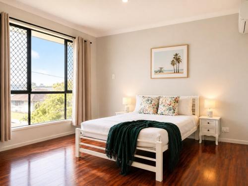 a white bedroom with a bed and a large window at 14A Convenient Ensuite Room in Coopers Plains in Brisbane