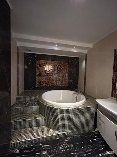 a bathroom with a tub and a tiled wall at Empire City in Karagandy