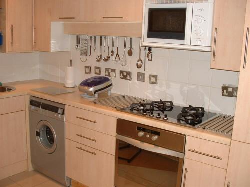 a kitchen with a stove and a microwave at Earle House Serviced Apartments in Crewe