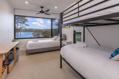 a bedroom with two beds and a large window at Seashells Lakeside Holiday Perfection in Smiths Lake
