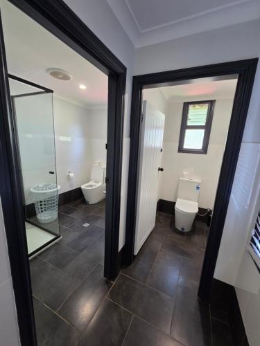 a bathroom with two toilets and a glass door at The Rec Hotel Waroona in Waroona