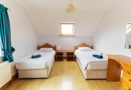 a bedroom with two beds and a window at 1 Bray Head View in Portmagee