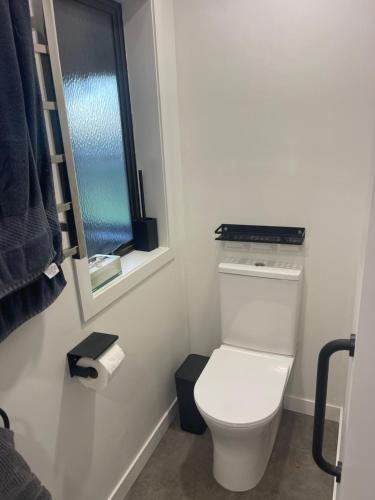 a bathroom with a white toilet and a window at Kaiapoi Village Le Shack in Kaiapoi