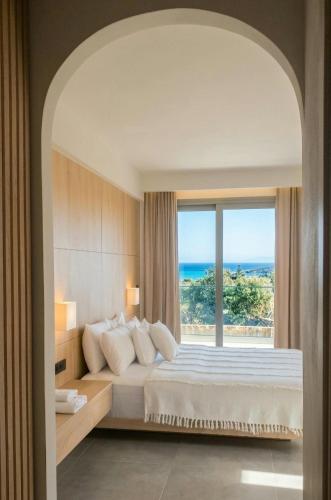 a bedroom with a large bed with a large window at Pnoé Sea View Suites in Limenas