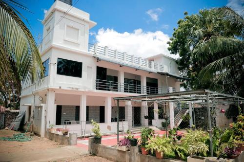a white house with a lot of plants at Hotel Jebasakthy in Kanyakumari
