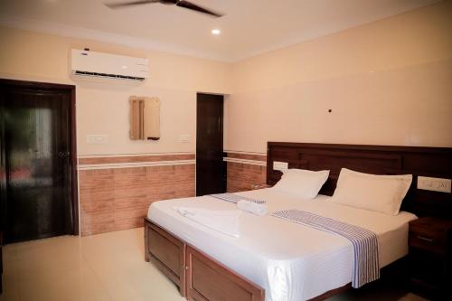 a bedroom with a large bed with white sheets at Hotel Jebasakthy in Kanyakumari