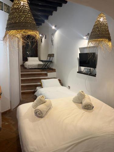 two beds in a room with a tv and two towels at Spinuzza Boutique Guesthouse Cefalù, Sicily in Cefalù