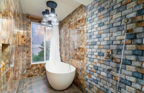 a bathroom with a bath tub in a brick wall at Ukulhas Villa Hotel & Spa in Ukulhas