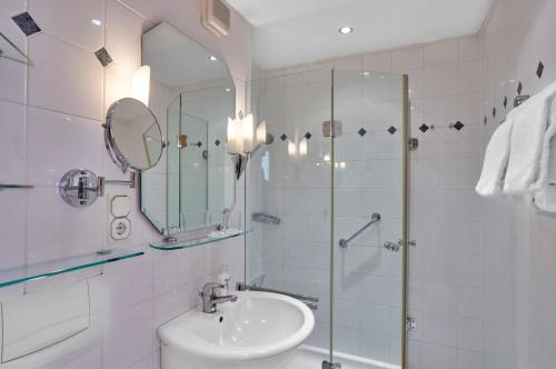 a white bathroom with a sink and a shower at Hotel Bayerischer Hof in Bad Füssing