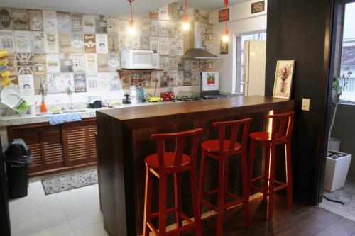 uma cozinha com três bancos vermelhos num bar em Pup Hostel SC em Florianópolis