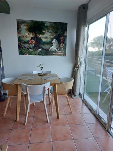 a dining room with a table and chairs and a window at CAP AZUR ILE du LEVANT in Île du Levant