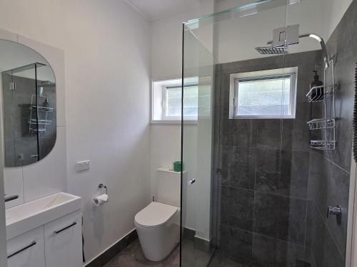 a bathroom with a toilet and a glass shower at Peninsula Caravan Park Cooktown in Cooktown