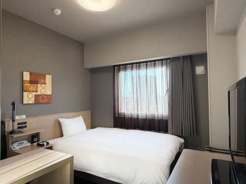 a hotel room with a bed and a window at Hotel Route-Inn Yanagawa Ekimae in Yanagawa