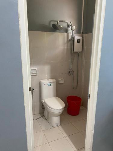 a bathroom with a toilet and a red bucket at Pineda Villa in Puerto Princesa City