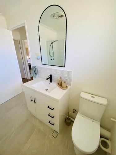 a bathroom with a white toilet and a mirror at Mariners Rest in Redland Bay