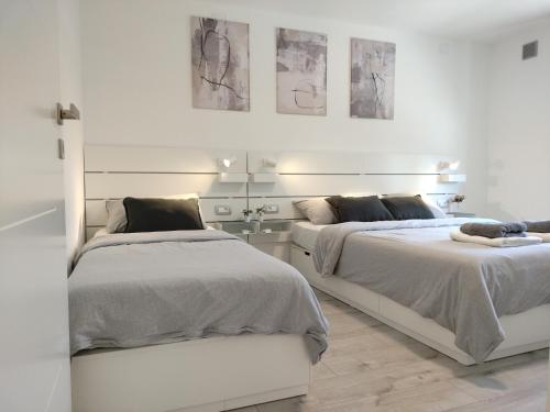 two beds in a white room with paintings on the wall at Ka6 Infinity Apartment - Vipava Valley in Ajdovščina