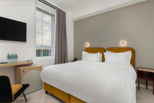 a bedroom with a large white bed and a window at Academy by Ambassadori in Kachretʼi