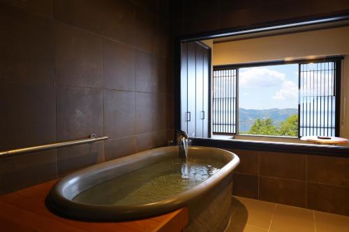 a bath tub in a bathroom with a window at Suwakoen in Suwa