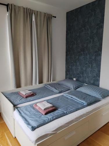 a bed with blue sheets and two towels on it at Royal Villa - HAWAII in Vrnjačka Banja