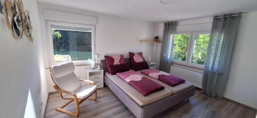a bedroom with a couch and a chair and windows at Ferienhaus an der Ölmühle in Heusweiler