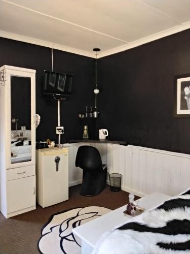 a bedroom with a black wall with a bed and a chair at Prosper Stud Guest House in Robertson