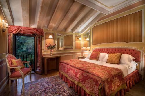 a bedroom with a bed and a chair and a window at Romantik Hotel Villa Margherita in Mira