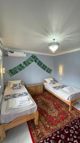 two beds in a room with a rug at Khiva Mahliyo in Khiva