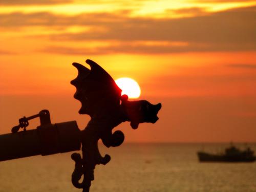a sunset over the ocean with a statue of a butterfly at Hosteria Farallon Dillon in Ballenita