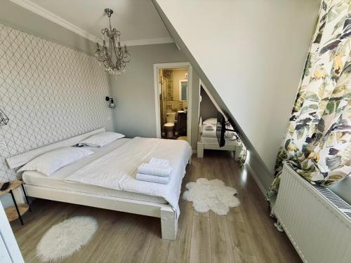 a bedroom with a white bed and a staircase at Doinita House in Borşa