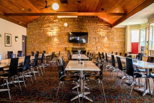 a dining room with tables and chairs and a brick wall at Lilac City Motor Inn & Steakhouse in Goulburn